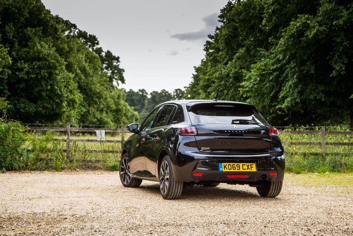 Black car in a green field with trees and a gravel road